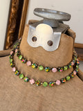 Close view of pink green and iridescent crystal necklace styled layered