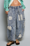 Washed blue jogger pants with crochet patch details, front view
